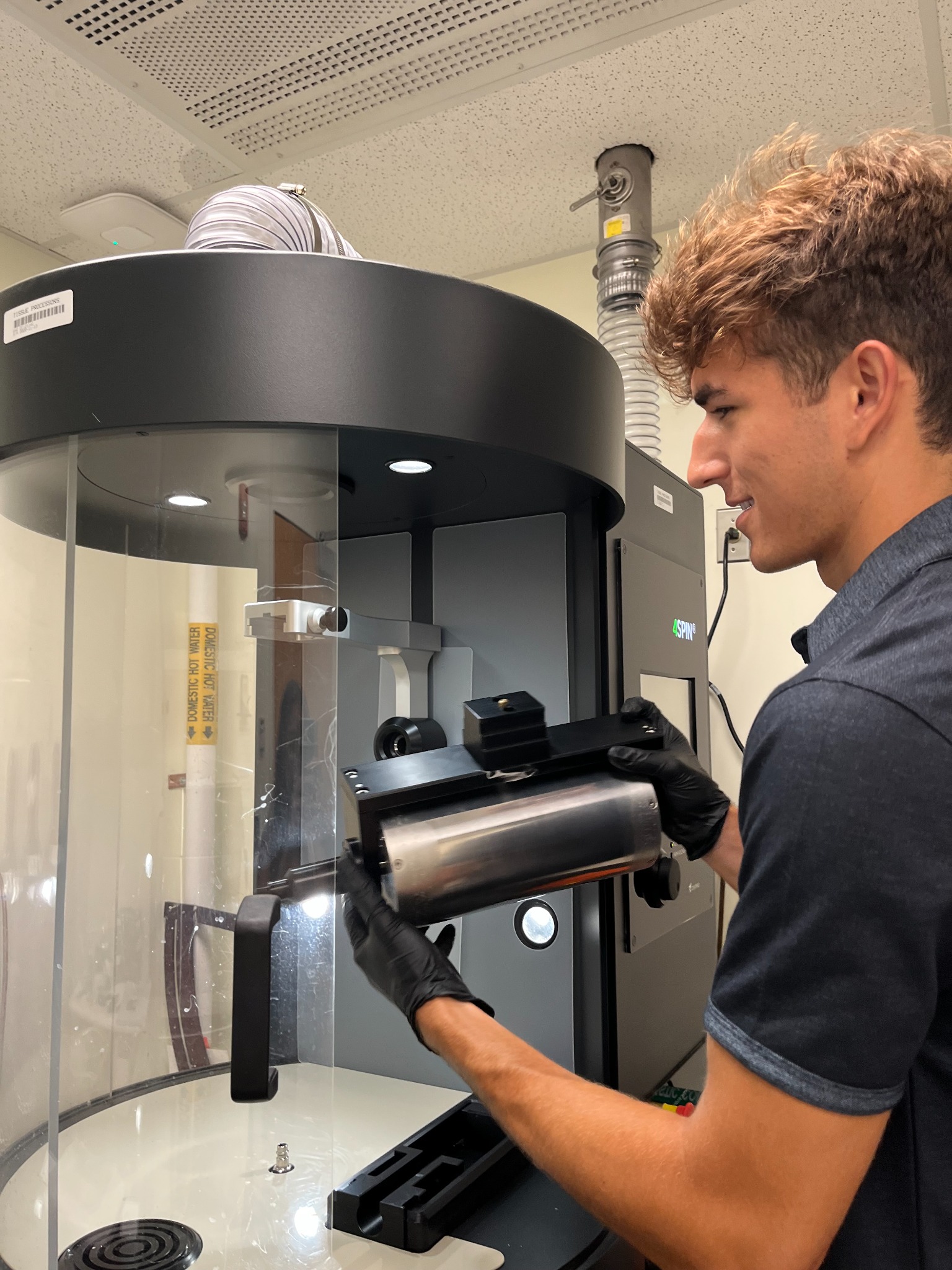 Eric handling a collector beside laboratory fabrication equipment.